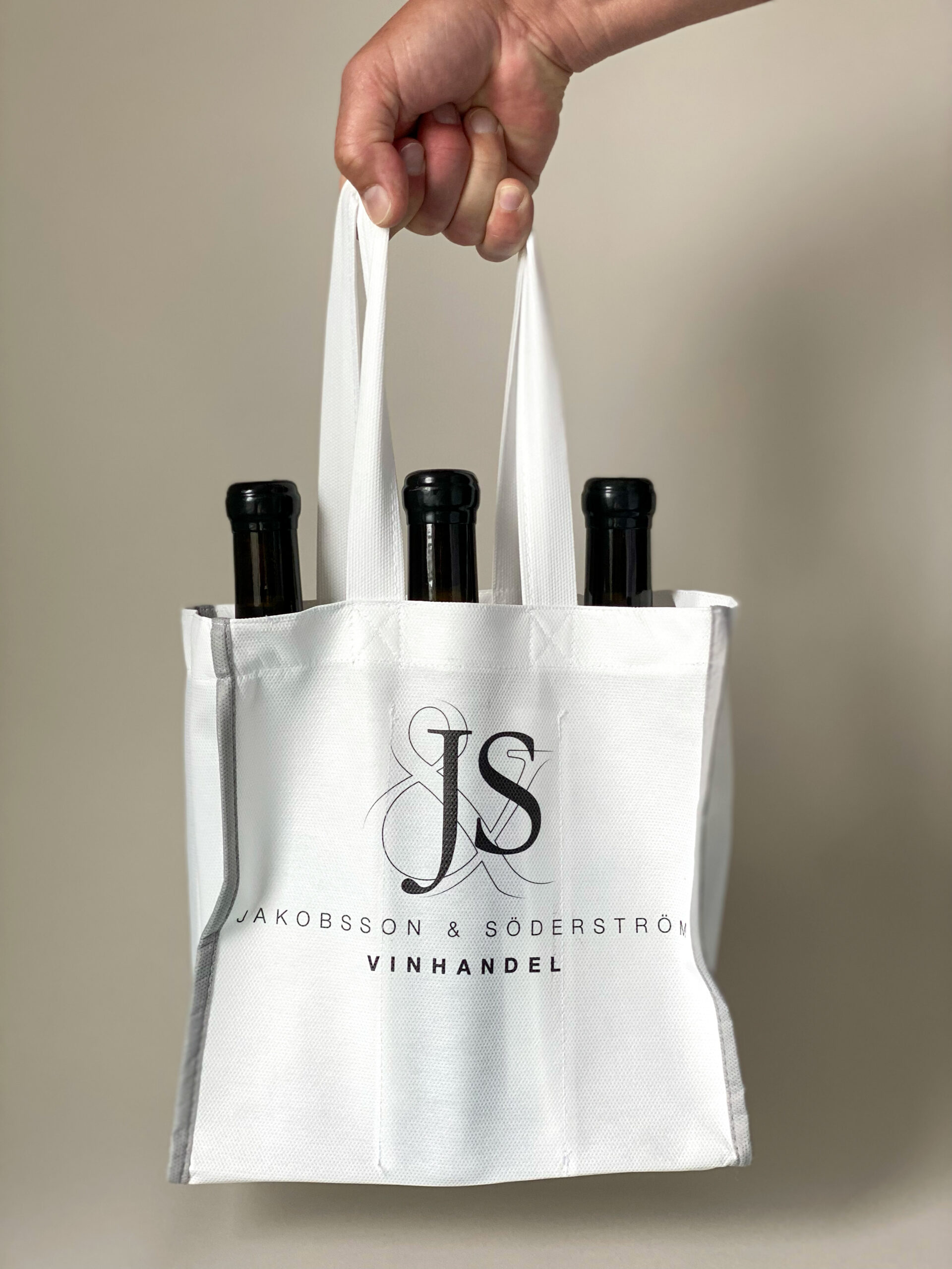 Återanvändbar vinpåse i non-woven med tryckt logotyp. Rymlig flaskpåse med handtag perfekt för butik och enkel att bära hem.