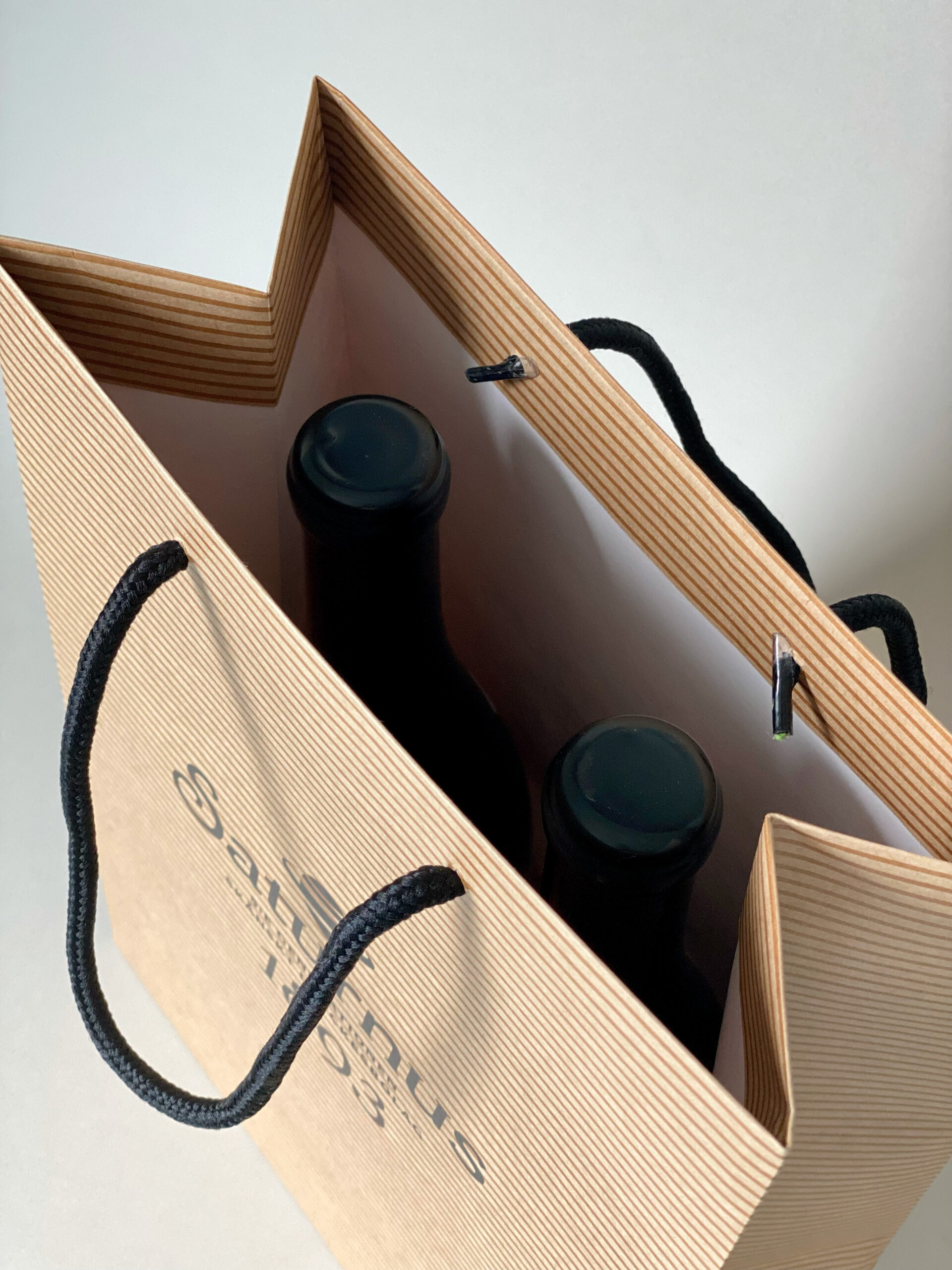 Insidan av flaskpåse i papper med svarta bomullshandtag.