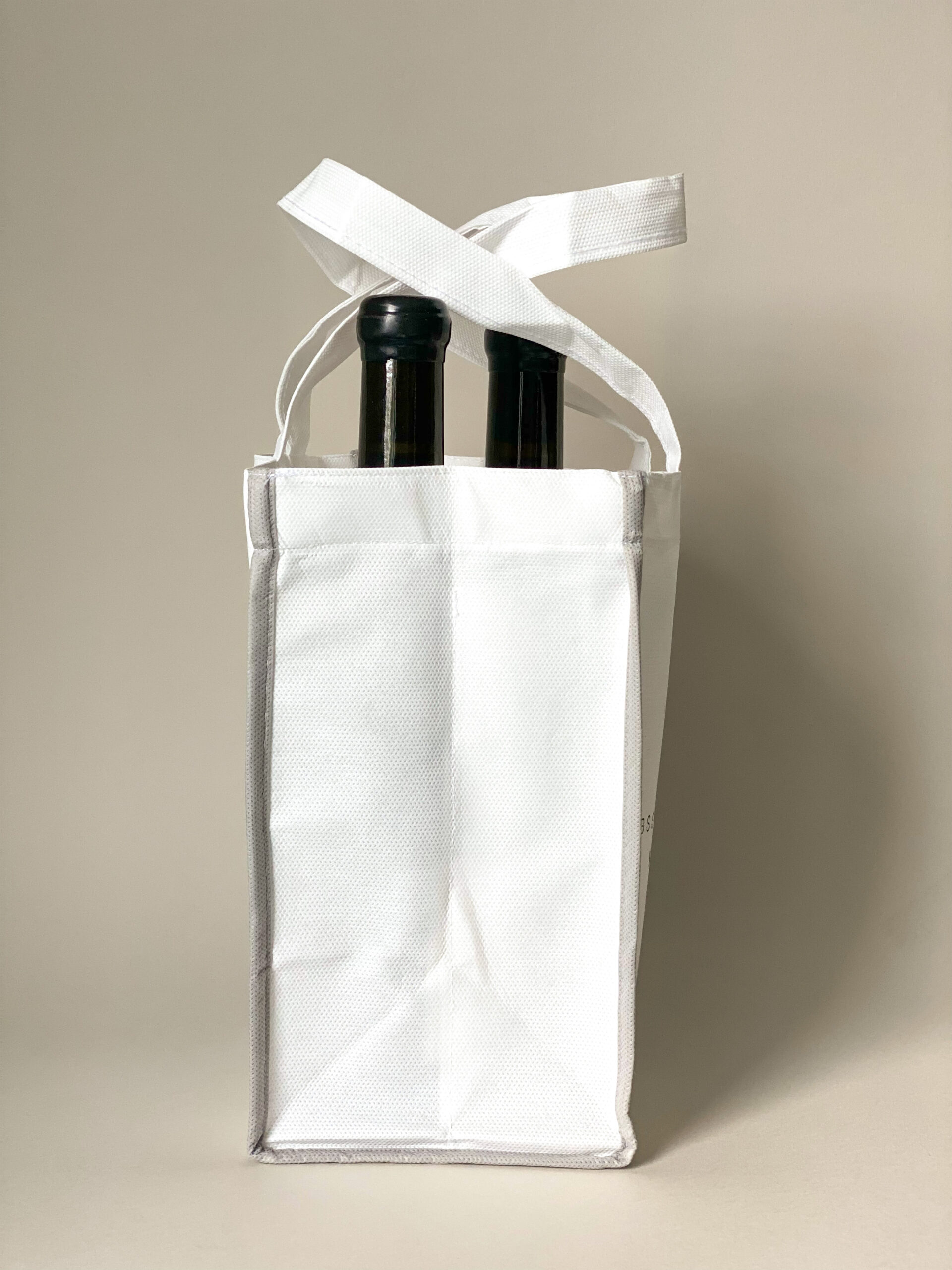Sidovy av vit flaskpåse i non-woven material med tryck, vinpåse med plats för flera flaskor.